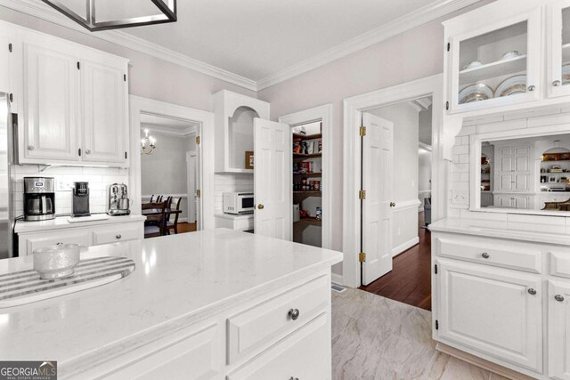 135 Mill Race Rd, Thomaston, GA 30286 - kitchen with crown molding, white microwave, white cabinetry, decorative backsplash, and glass insert cabinets