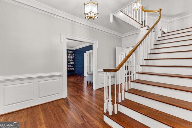 135 Mill Race Rd, Thomaston, GA 30286 - stairway featuring a chandelier, ornamental molding, wood finished floors, a wainscoted wall, and a decorative wall