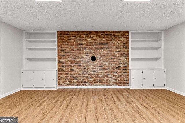 135 Mill Race Rd, Thomaston, GA 30286 - unfurnished living room with built in features, baseboards, wood finished floors, and brick wall