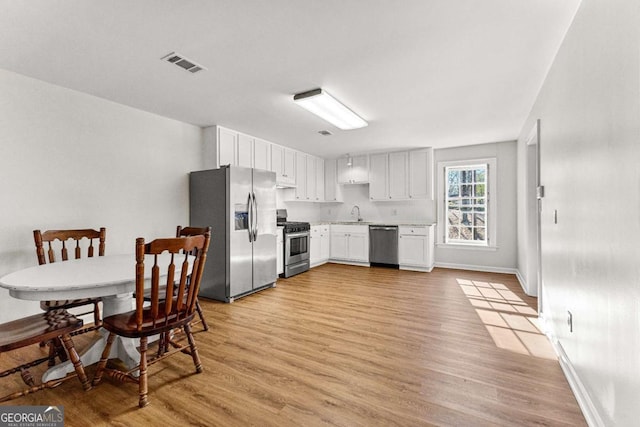 135 Mill Race Rd, Thomaston, GA 30286 - kitchen with appliances with stainless steel finishes, light wood-style floors, light countertops, white cabinetry, and baseboards
