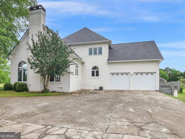 474 N Rover Rd, Williamson, GA 30292 - back of property featuring a chimney, a garage, driveway, stucco siding, and a shingled roof