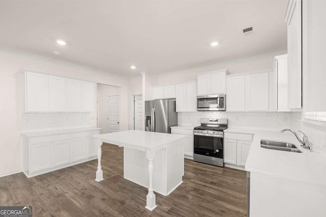 1159 Blue Juniper Cir, Loganville, GA 30052 - kitchen featuring appliances with stainless steel finishes, a sink, tasteful backsplash, a center island, and crown molding