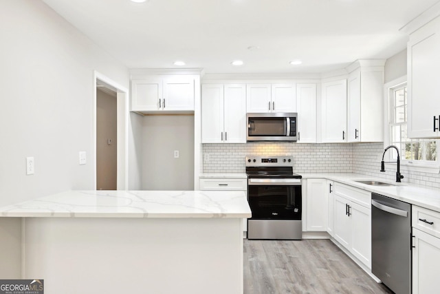 1483 Madison Rd, Monticello, GA 31064 - kitchen featuring stainless steel appliances, a sink, light wood-style floors, white cabinets, and light stone countertops