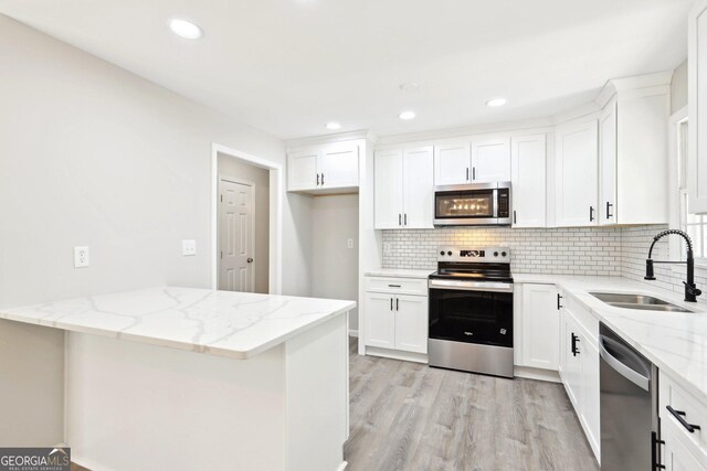 1483 Madison Rd, Monticello, GA 31064 - kitchen featuring stainless steel appliances, a sink, light wood-style floors, decorative backsplash, and light stone countertops