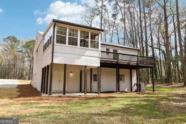 1483 Madison Rd, Monticello, GA 31064 - rear view of property with central air condition unit, a wooden deck, brick siding, a yard, and a sunroom