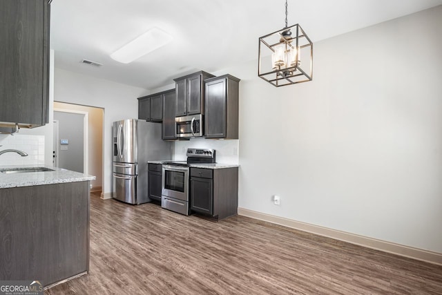 1010 Holliday Pass, Griffin, GA 30223 - kitchen with appliances with stainless steel finishes, dark wood-style floors, tasteful backsplash, a chandelier, and light stone counters