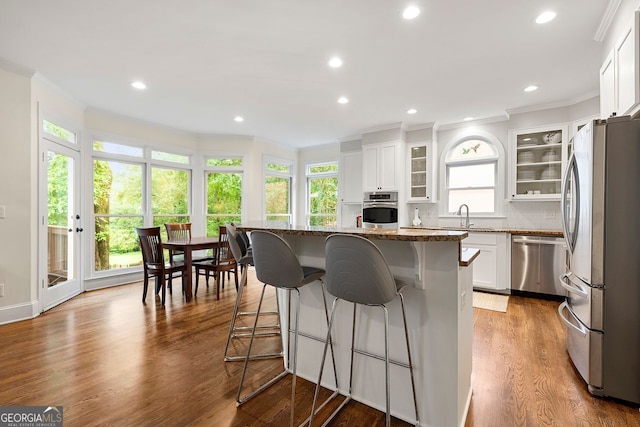 3714 Westbrooke Cir, Brookhaven, GA 30319 - kitchen with appliances with stainless steel finishes, crown molding, a sink, dark stone counters, and a kitchen bar