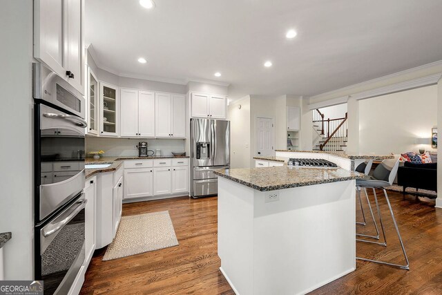 3714 Westbrooke Cir, Brookhaven, GA 30319 - kitchen with appliances with stainless steel finishes, ornamental molding, a breakfast bar, white cabinets, and glass insert cabinets