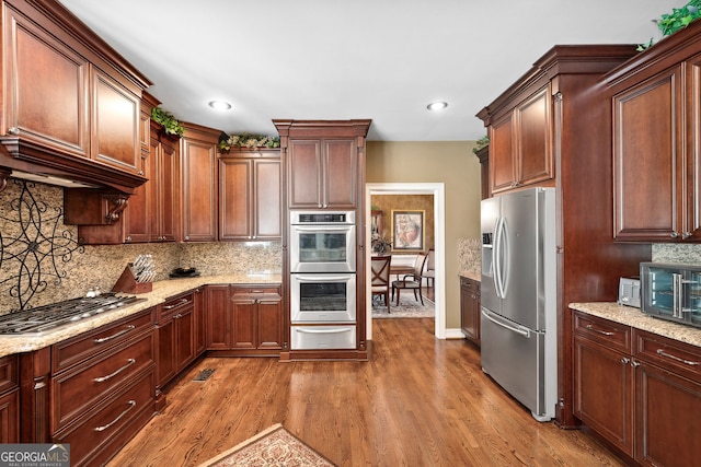 3495 Mill Bridge Dr, Marietta, GA 30062 - kitchen featuring stainless steel appliances, a warming drawer, wood finished floors, decorative backsplash, and light stone counters