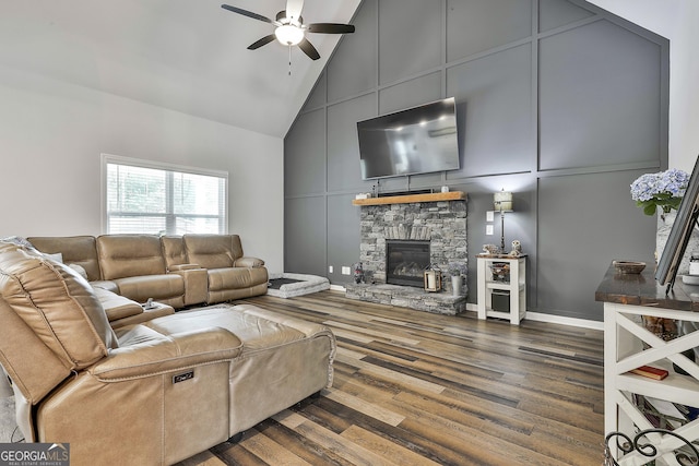 390 Cushing St, Senoia, GA 30276 - living room featuring high vaulted ceiling, a ceiling fan, a decorative wall, a stone fireplace, and dark wood-style flooring