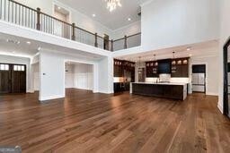 320 Dodd Ln, Alpharetta, GA 30005 - unfurnished living room with a towering ceiling, a chandelier, dark wood finished floors, ornamental molding, and recessed lighting