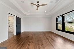 320 Dodd Ln, Alpharetta, GA 30005 - empty room with a raised ceiling, a barn door, ornamental molding, wood finished floors, and a ceiling fan