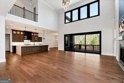320 Dodd Ln, Alpharetta, GA 30005 - unfurnished living room featuring a glass covered fireplace, a high ceiling, ornamental molding, a chandelier, and dark wood-style flooring