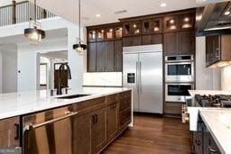 320 Dodd Ln, Alpharetta, GA 30005 - kitchen featuring stainless steel appliances, dark brown cabinets, light countertops, dark wood-style flooring, and pendant lighting