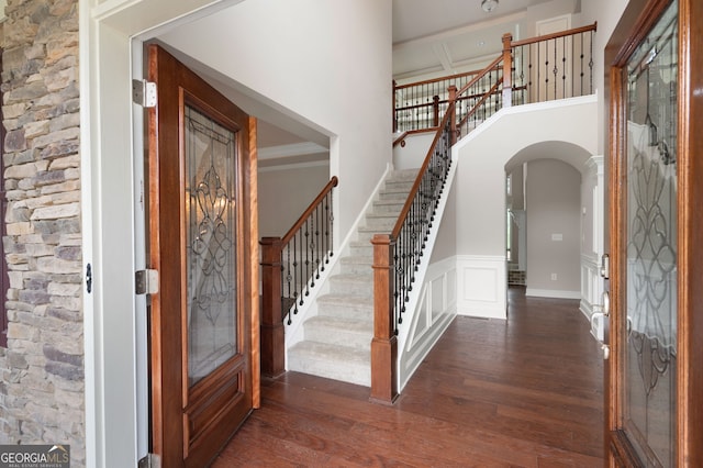 6585 Canyon Cv, Cumming, GA 30028 - entryway with dark wood-type flooring, arched walkways, stairway, a towering ceiling, and a wainscoted wall