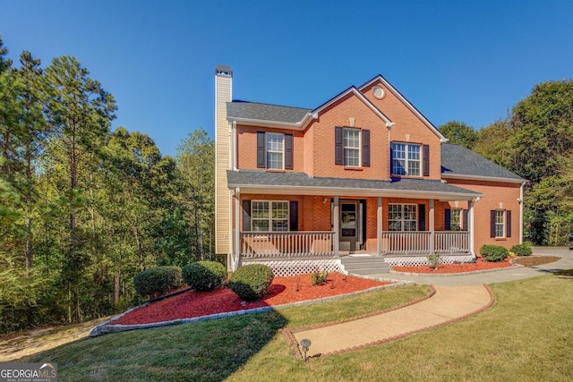 2436 Green Hollow Ct, Conyers, GA 30012 - traditional-style house featuring a chimney, a front yard, covered porch, and brick siding