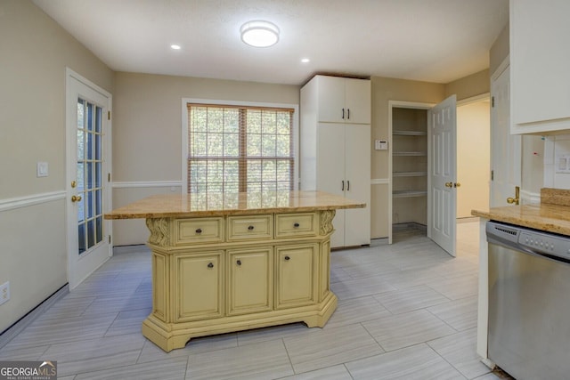 2436 Green Hollow Ct, Conyers, GA 30012 - kitchen with stainless steel dishwasher, cream cabinetry, light stone counters, a kitchen island, and recessed lighting