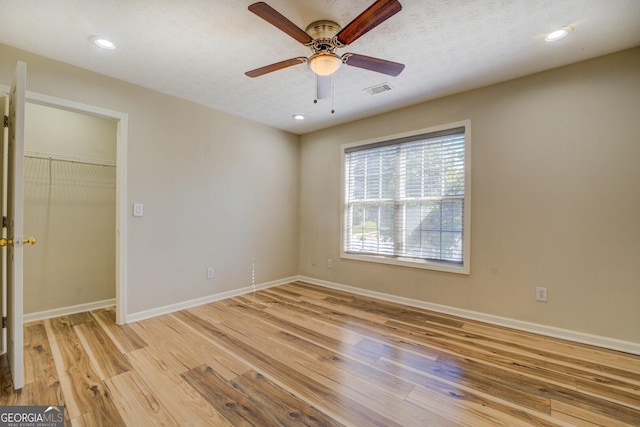 2436 Green Hollow Ct, Conyers, GA 30012 - unfurnished bedroom with light wood finished floors, baseboards, a walk in closet, a ceiling fan, and recessed lighting