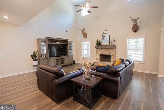 337 Paynes Lake Rd, Carrollton, GA 30116 - living room featuring wood finished floors, a ceiling fan, baseboards, a fireplace, and a high ceiling