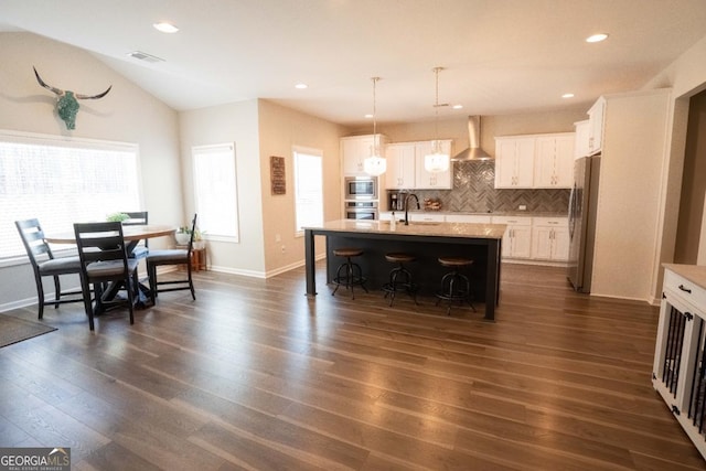 337 Paynes Lake Rd, Carrollton, GA 30116 - kitchen with wall chimney exhaust hood, appliances with stainless steel finishes, a breakfast bar area, tasteful backsplash, and white cabinets