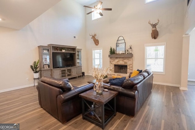 337 Paynes Lake Rd, Carrollton, GA 30116 - living room with a brick fireplace, wood finished floors, ceiling fan, baseboards, and a towering ceiling