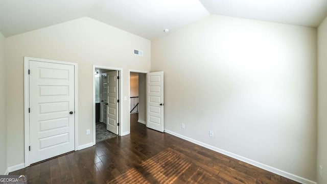 8744 Hamil Ct, Douglasville, GA 30135 - unfurnished bedroom featuring dark wood finished floors, baseboards, high vaulted ceiling, and ensuite bathroom