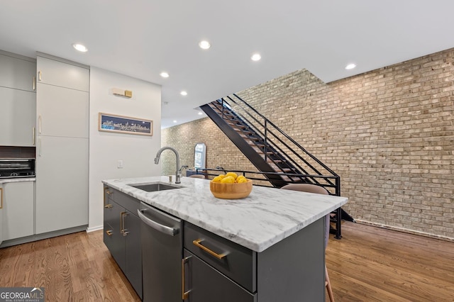 1308 NE Fernwood Cir NE, Atlanta, GA 30319 - kitchen with a sink, brick wall, dishwasher, a center island with sink, and light wood-style floors