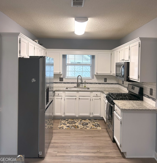165 Woodgate Cir, Fayetteville, GA 30214 - kitchen with appliances with stainless steel finishes, a sink, a textured ceiling, white cabinetry, and decorative backsplash