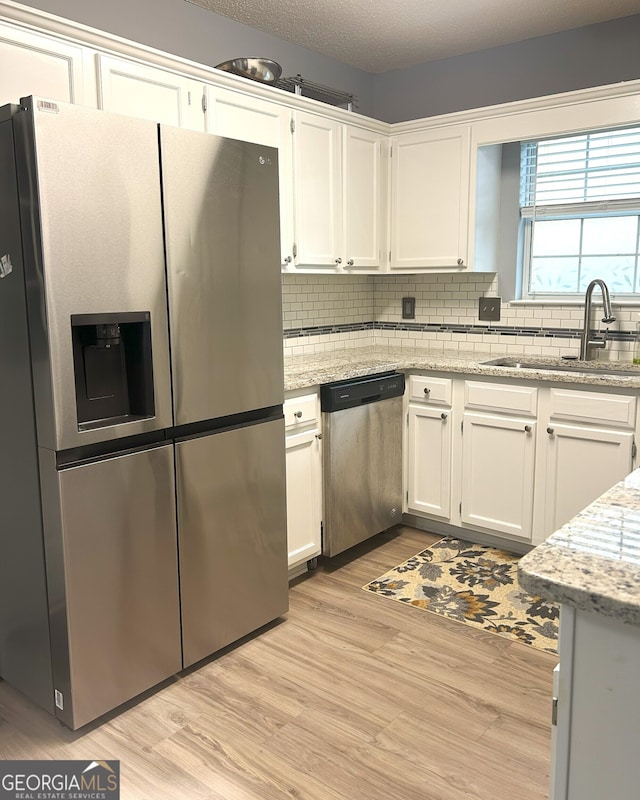 165 Woodgate Cir, Fayetteville, GA 30214 - kitchen with appliances with stainless steel finishes, a sink, light wood-style floors, and white cabinetry