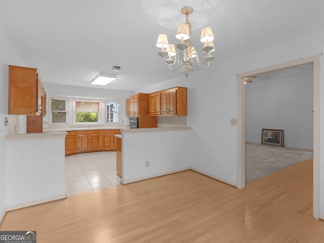 114 Overlook Dr, Mcdonough, GA 30252 - kitchen featuring a sink, a peninsula, a chandelier, and light wood-style floors