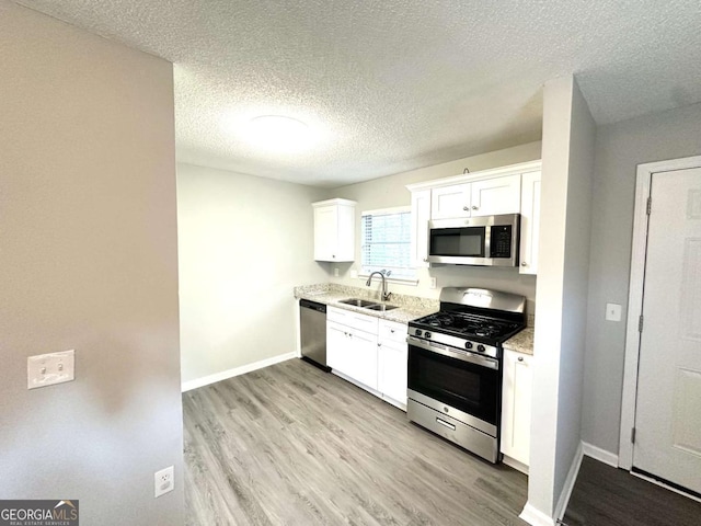 3170 W Point Cir, Douglasville, GA 30135 - kitchen featuring appliances with stainless steel finishes, white cabinets, light wood finished floors, a textured ceiling, and baseboards