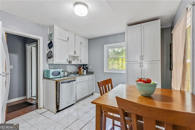 118 Greenwood St, Fairburn, GA 30213 - kitchen featuring stainless steel dishwasher, white microwave, white cabinetry, a sink, and freestanding refrigerator