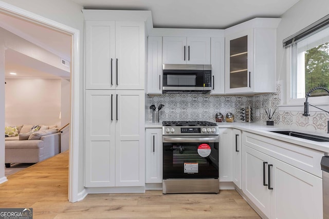 2012 Variations Dr NE, Atlanta, GA 30329 - kitchen with appliances with stainless steel finishes, a sink, light countertops, white cabinetry, and decorative backsplash