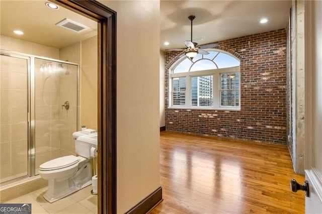 3180 Mathieson Dr NE Unit 1401, Atlanta, GA 30305 - full bath featuring brick wall, ceiling fan, toilet, a stall shower, and wood finished floors