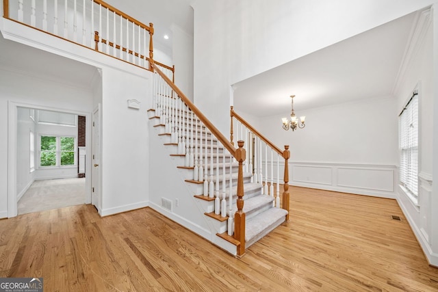 5190 Beech Forest Dr, Lilburn, GA 30047 - stairs featuring wood finished floors, a chandelier, crown molding, a decorative wall, and baseboards