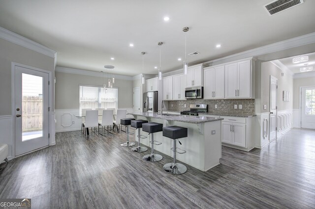 158 Bryon Ln, Acworth, GA 30102 - kitchen featuring appliances with stainless steel finishes, ornamental molding, a breakfast bar area, a kitchen island with sink, and white cabinetry