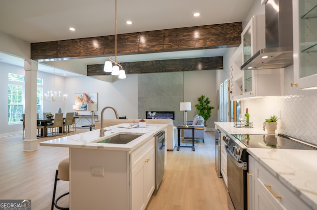 4366 Bradley Dr SW, Snellville, GA 30039 - kitchen with stainless steel appliances, a sink, a chandelier, light wood-style floors, and wall chimney range hood