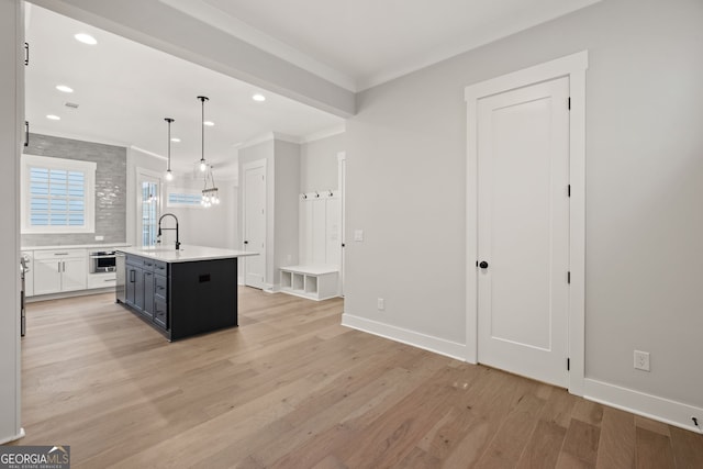 4002 Potter Way, Woodstock, GA 30188 - kitchen with light wood-style floors, light countertops, a sink, crown molding, and a kitchen island with sink