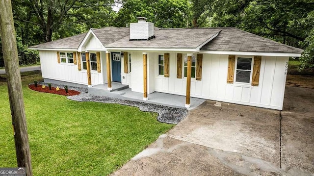 3978 Oglesby Rd, Powder Springs, GA 30127 - modern farmhouse featuring board and batten siding, covered porch, a chimney, roof with shingles, and a front lawn