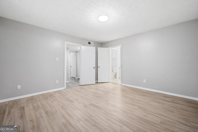 113 Tuxworth Cir, Decatur, GA 30033 - unfurnished bedroom with baseboards, light wood-type flooring, ensuite bathroom, and a textured ceiling