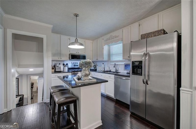 123 Mill Ln, Dallas, GA 30157 - kitchen featuring appliances with stainless steel finishes, dark countertops, white cabinetry, a center island, and a textured ceiling