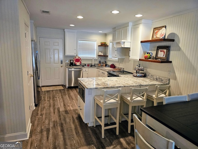 127 Azalea Rd Apt A103, Midway, GA 31320 - kitchen with open shelves, stainless steel appliances, a peninsula, dark wood-type flooring, and white cabinetry