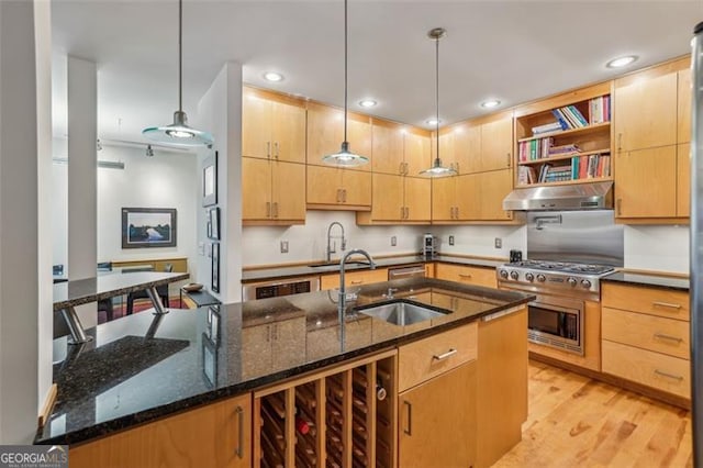 6550 Bluewaters Dr, Flowery Branch, GA 30542 - kitchen featuring under cabinet range hood, a sink, dark stone counters, light wood finished floors, and recessed lighting
