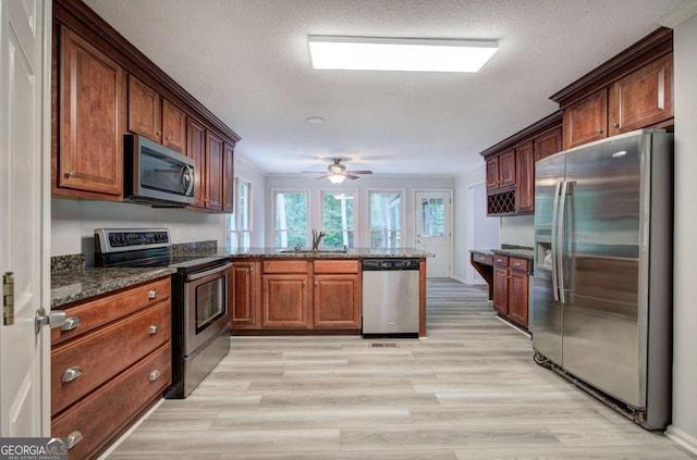 23 Timberlake Pointe NE, Cartersville, GA 30121 - kitchen featuring appliances with stainless steel finishes, a peninsula, dark stone counters, light wood-style flooring, and a sink