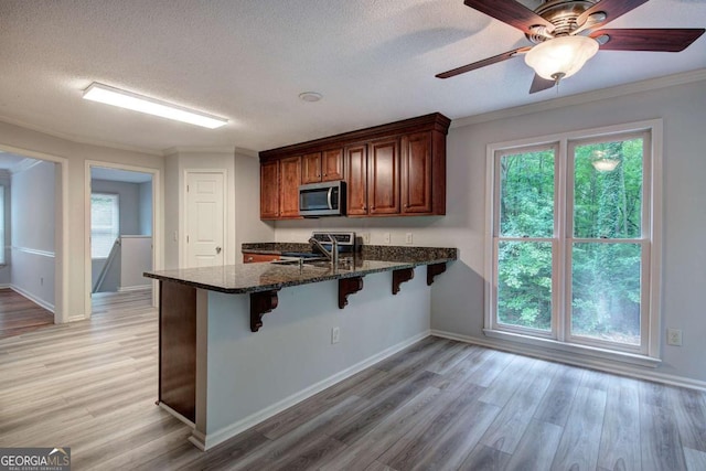 23 Timberlake Pointe NE, Cartersville, GA 30121 - kitchen featuring appliances with stainless steel finishes, a peninsula, a breakfast bar area, light wood-style flooring, and a textured ceiling