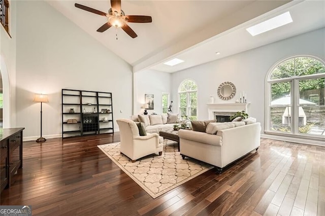 5940 Plantation Dr, Roswell, GA 30075 - living room featuring a glass covered fireplace, high vaulted ceiling, dark wood-type flooring, a ceiling fan, and a skylight