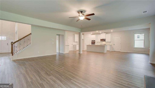 165 Cooper Cv E, Fayetteville, GA 30215 - unfurnished living room featuring a ceiling fan, baseboards, stairway, and dark wood-style floors
