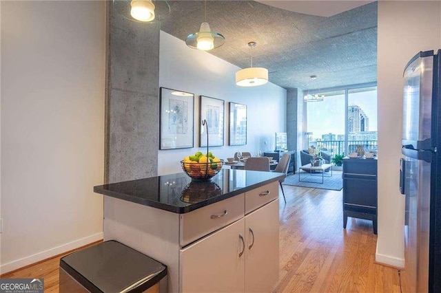 860 Peachtree St NE Unit 1613, Atlanta, GA 30308 - kitchen featuring light wood-style flooring, floor to ceiling windows, freestanding refrigerator, pendant lighting, and dark countertops
