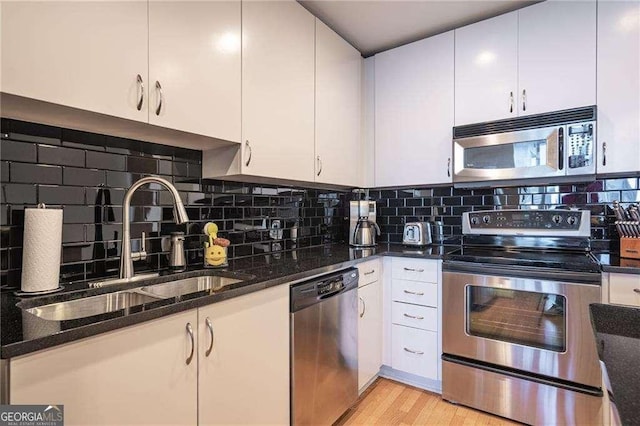 860 Peachtree St NE Unit 1613, Atlanta, GA 30308 - kitchen with appliances with stainless steel finishes, white cabinetry, dark stone counters, and tasteful backsplash
