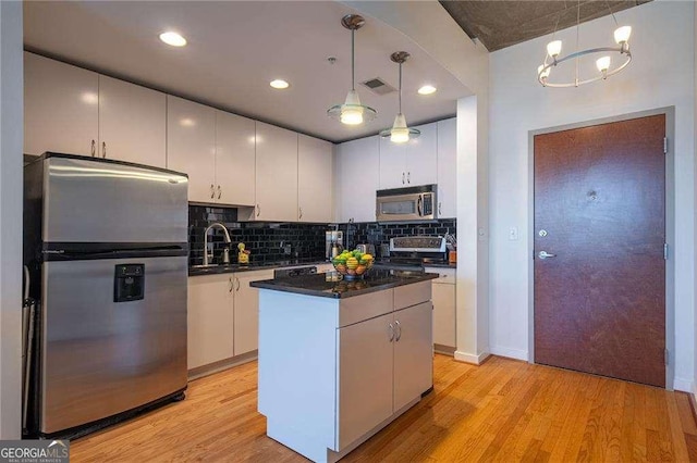 860 Peachtree St NE Unit 1613, Atlanta, GA 30308 - kitchen with stainless steel appliances, dark countertops, light wood finished floors, a kitchen island, and backsplash